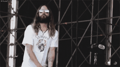 a man with long hair and a beard wearing sunglasses and a shirt that says le reiseh
