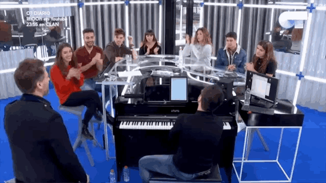 a group of people sitting around a piano with diario written on the wall