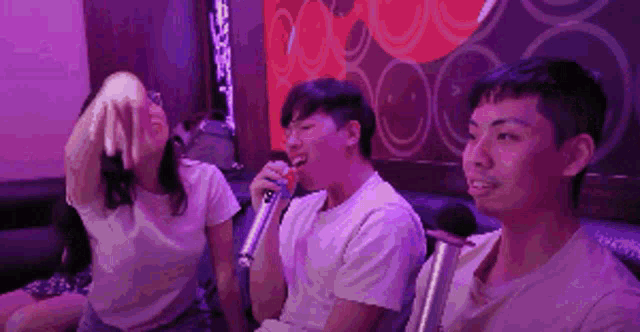 a group of people singing into microphones in a karaoke room .