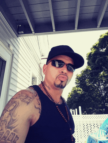 a man wearing sunglasses and a hat has a tattoo on his arm that says " i love you "