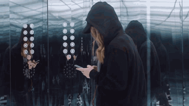 a woman in a black hoodie looking at her phone