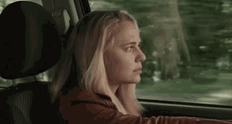 a woman is sitting in the back seat of a car and looking out the window .