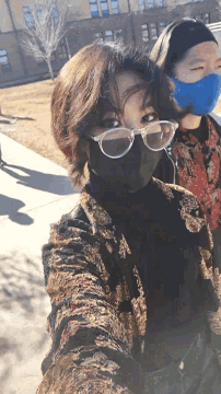 a woman wearing glasses and a blue mask is standing next to another woman