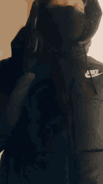 a man wearing a black nike hoodie and a black mask