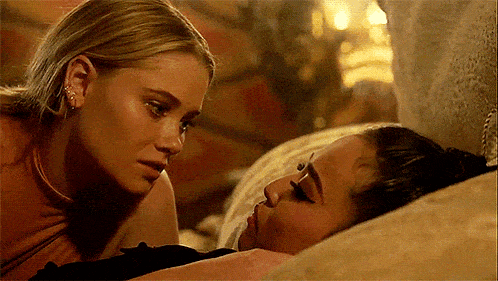 two women are laying on a bed looking at each other