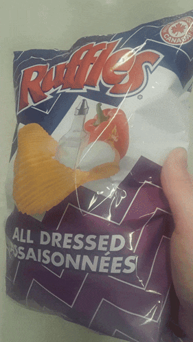 a person is holding a bag of ruffles all dressed seasoned chips
