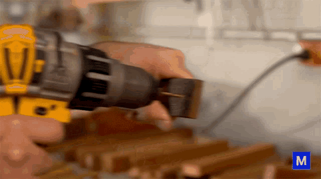 a close up of a person using a drill with the letter m in the lower right corner