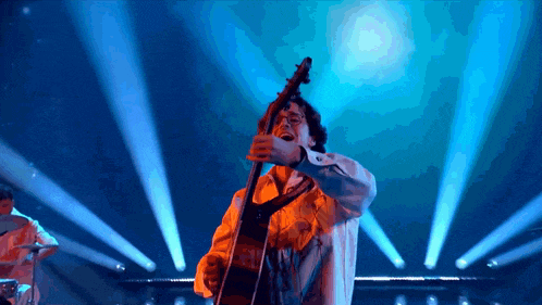 a man playing a guitar on a stage with blue lights