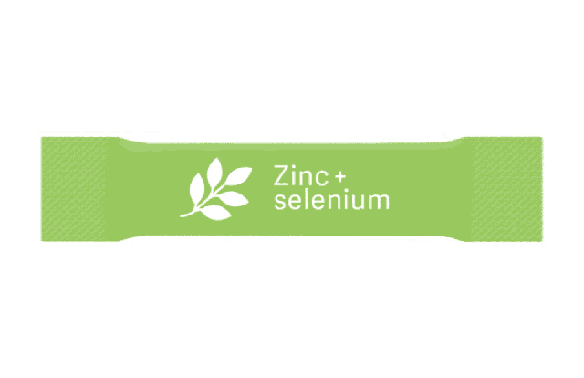 a green packet of zinc and selenium is being opened