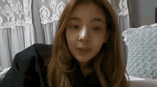 a woman with long blonde hair is sitting on a bed
