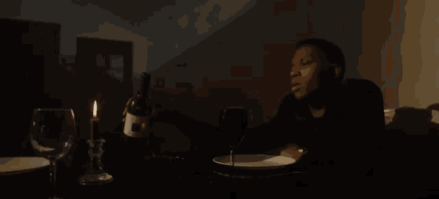 a man sitting at a table with a bottle of wine and a glass