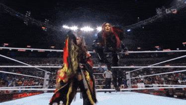 two women wrestling in a ring with a referee and a crowd watching