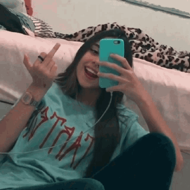 a girl is taking a picture of herself with her phone while wearing a t-shirt that says " ita "