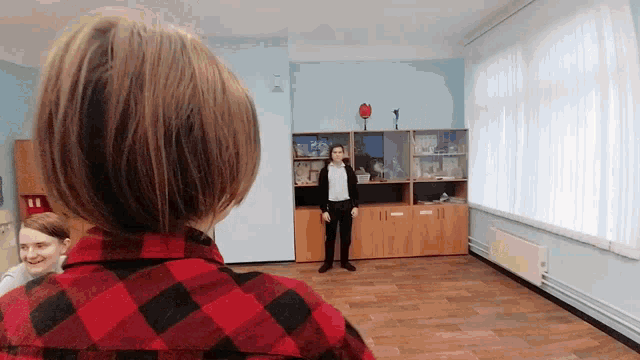 a woman in a plaid shirt stands in a room