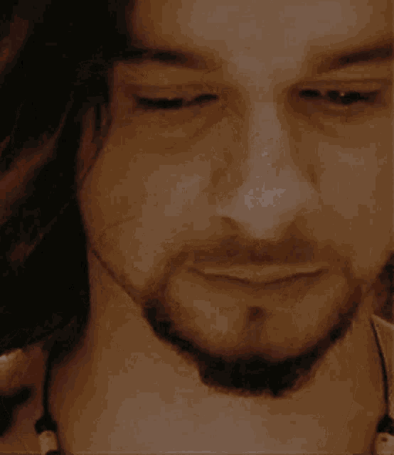 a close up of a man 's face with a beard and a white shirt
