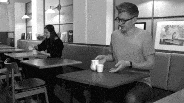 a man and a woman sit at a table in a restaurant with a picture of a bird on the wall