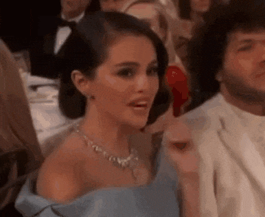 a woman in a blue dress is holding a red object in her hand in a crowd of people .