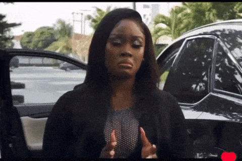 a woman is standing in front of a black car and making a face