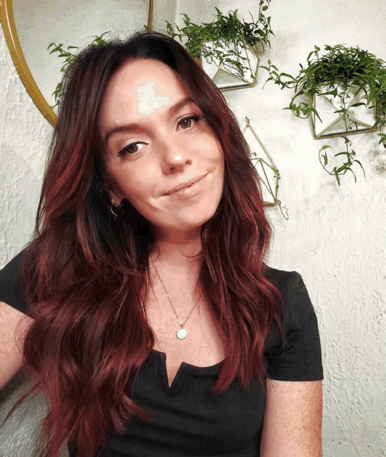 a woman with red hair is wearing a black top