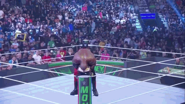a wrestler is kneeling on a green cylinder with the word money on it