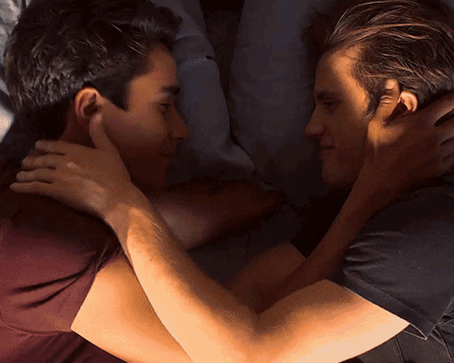 a man in a maroon shirt is laying next to another man
