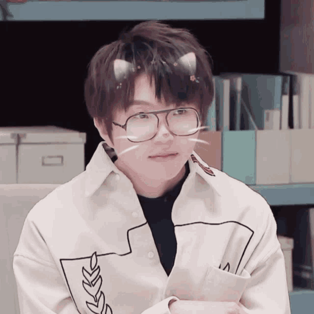 a young man wearing glasses and a white shirt with a leaf design on the sleeve