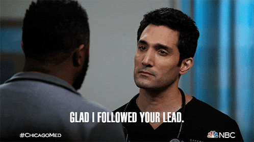 a man with a stethoscope around his neck talks to another man and says " glad i followed your lead "