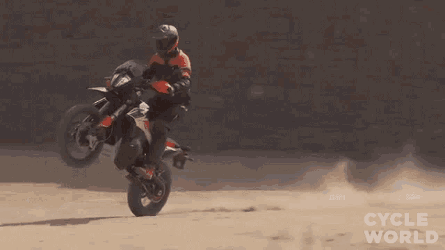 a man is riding a dirt bike on a dirt road with cycle world written in the corner