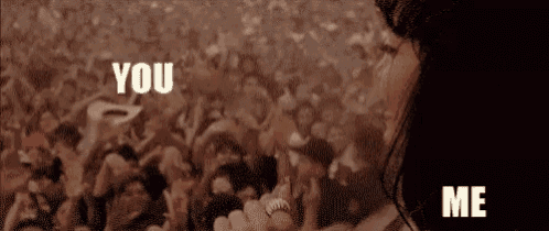 a woman is holding a microphone in front of a crowd of people and says `` you '' and `` me '' .