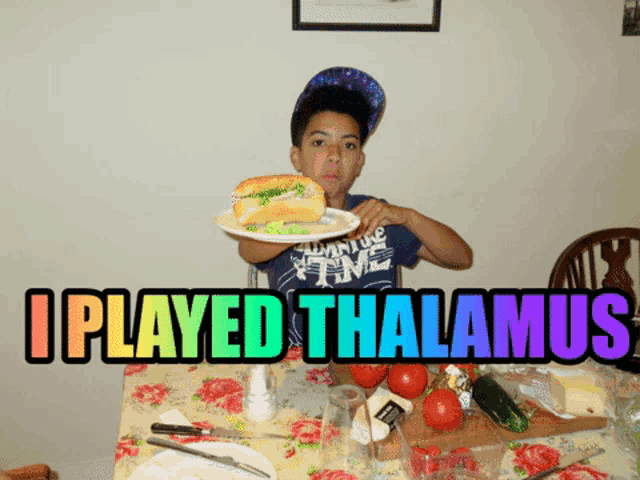 a boy sitting at a table with a plate of food and a sign that says i played thalamaus