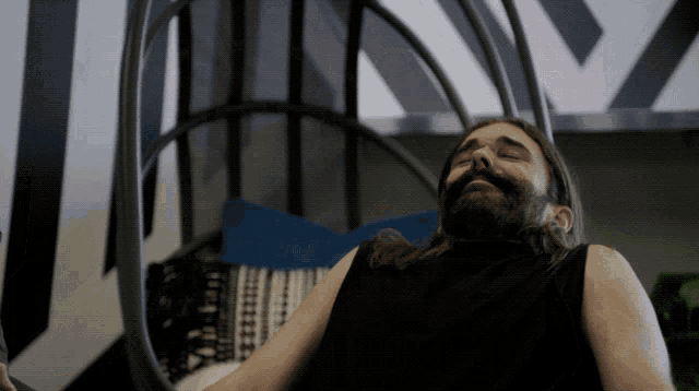 a man with a beard is sitting in a chair with his eyes closed