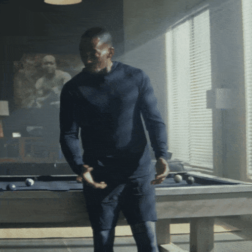 a man stands in front of a pool table in a dark room