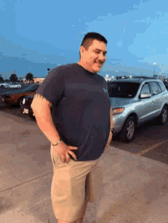 a man wearing a blue shirt and khaki shorts is standing in a parking lot