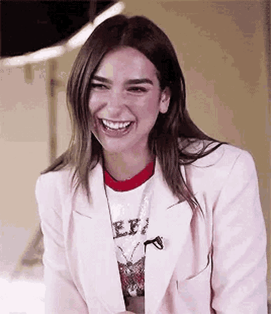 a woman wearing a pink jacket and a red t-shirt is laughing .
