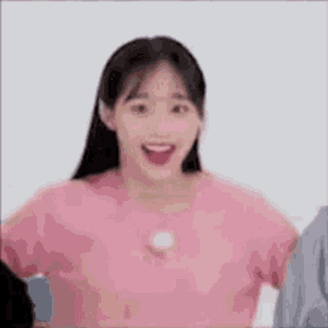 a woman in a pink shirt is smiling with her mouth open .