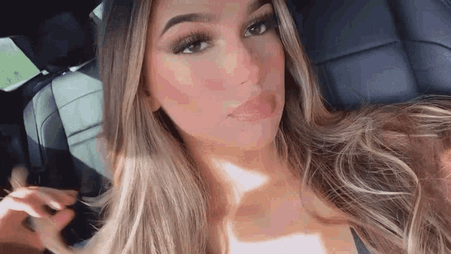 a woman is sitting in the back seat of a car looking at the camera .