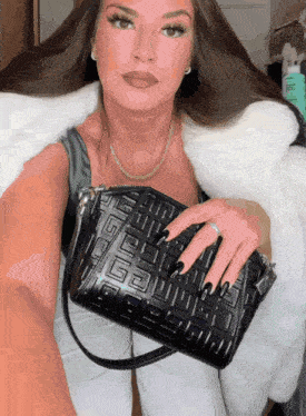 a woman is holding a black purse with a greek key pattern