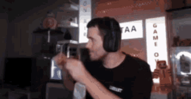 a man wearing headphones is dancing in a room with a sign that says game on it