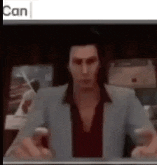 a man in a suit and red shirt is sitting in front of a computer screen .