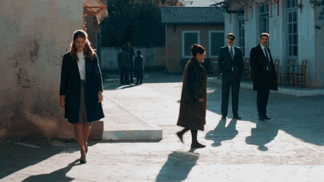 a group of people standing on a sidewalk including a woman