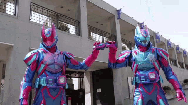 two kamen riders standing next to each other in front of a building .