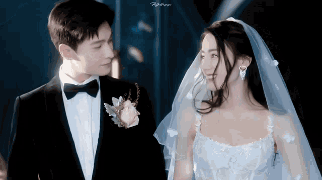 a man in a tuxedo and a woman in a white dress are standing next to each other