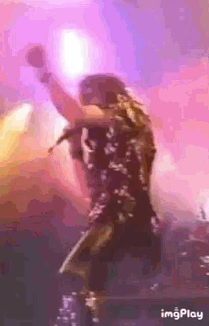 a man is singing into a microphone on a stage in front of a purple background .