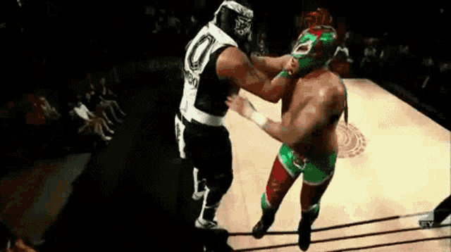 two wrestlers are fighting each other in a ring .
