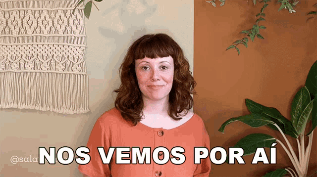 a woman stands in front of a wall with the words nos vemos por ai above her
