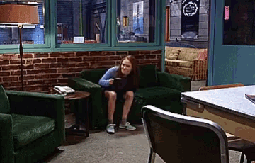 a woman is sitting on a green chair in a room