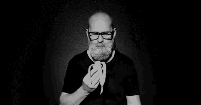 a man with glasses and a beard eating a banana