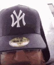 a man wearing a new york yankees hat looks at the camera