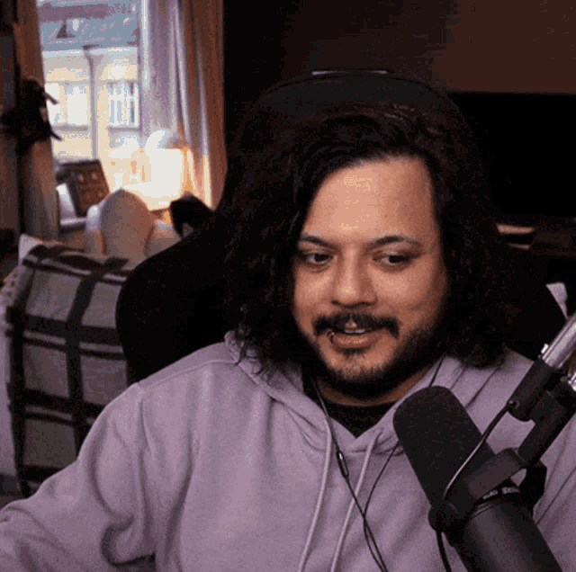 a man with long hair and a beard is sitting in front of a microphone wearing headphones