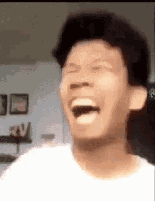 a man is laughing with his mouth open and his tongue out while wearing a white shirt .